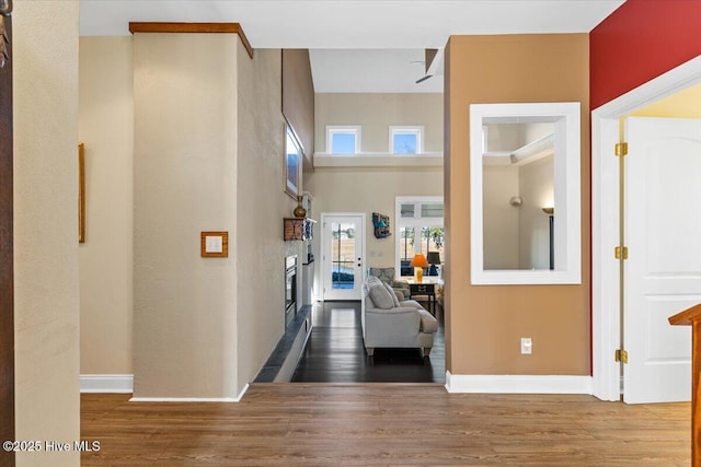 hall featuring a high ceiling, baseboards, and wood finished floors