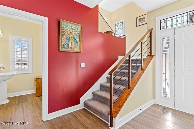 foyer featuring stairs, visible vents, wood finished floors, and baseboards
