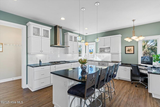 kitchen with white cabinetry, wall chimney range hood, and a wealth of natural light