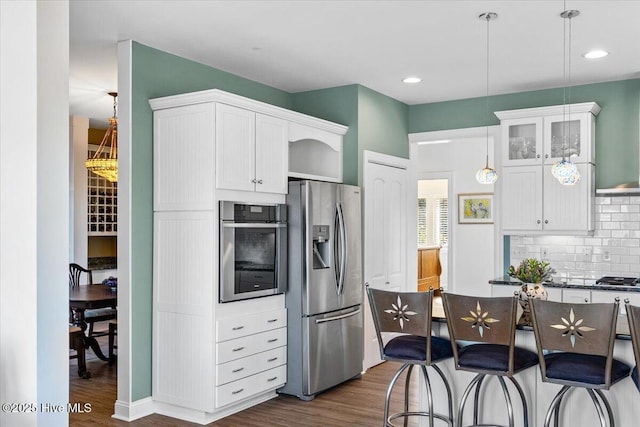 kitchen featuring stainless steel appliances, tasteful backsplash, dark wood-type flooring, and white cabinets