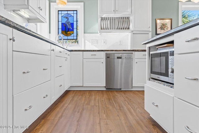 kitchen featuring appliances with stainless steel finishes, tasteful backsplash, white cabinetry, and wood finished floors