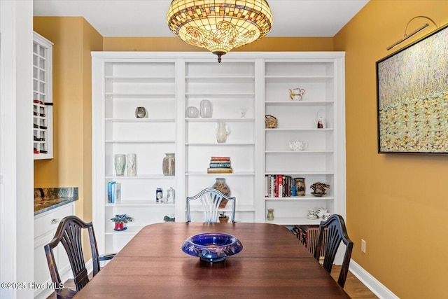 dining room featuring built in shelves, baseboards, and dark wood-style floors