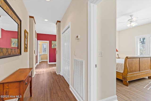 corridor featuring baseboards, visible vents, and wood finished floors