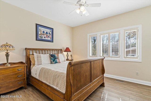 bedroom with baseboards, visible vents, a ceiling fan, and wood finished floors