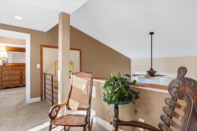 sitting room with a ceiling fan, lofted ceiling, light colored carpet, and baseboards