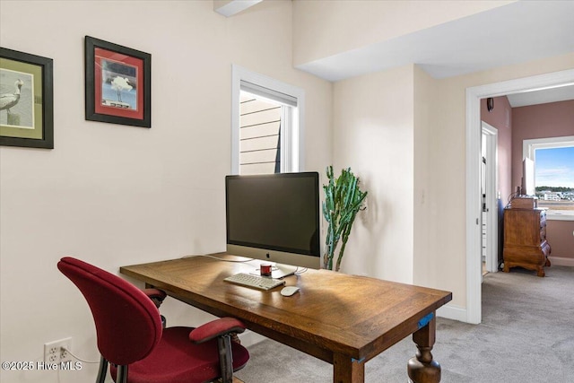 office area featuring light carpet and baseboards