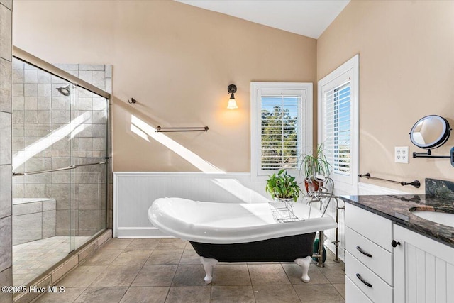 full bathroom featuring lofted ceiling, a freestanding bath, wainscoting, and a shower stall