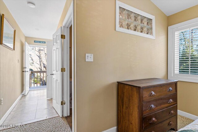 hallway featuring light tile patterned flooring, baseboards, and a healthy amount of sunlight