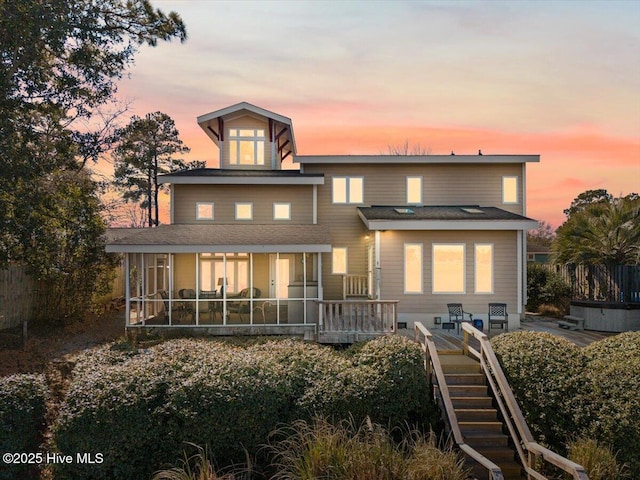 back of house with stairs, a wooden deck, fence, and a sunroom