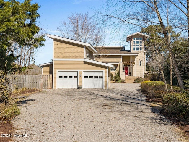 view of front of house featuring driveway, a garage, and fence