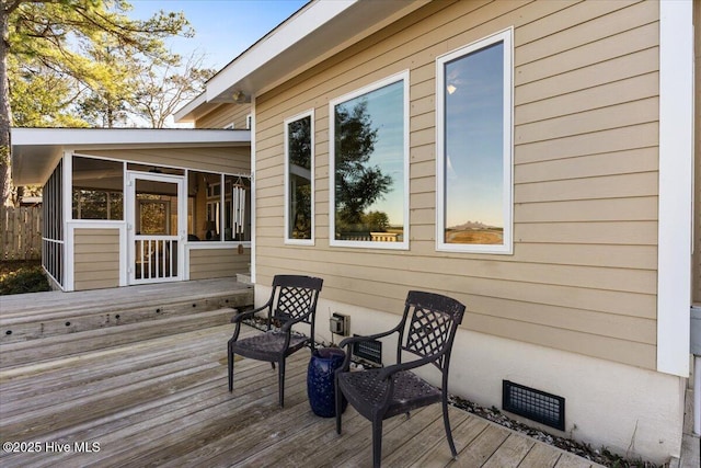 wooden deck with a sunroom and visible vents