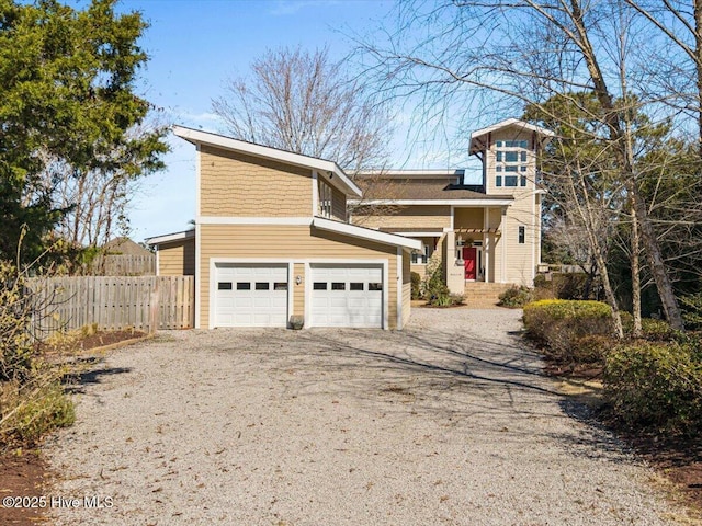 view of front of house featuring driveway, an attached garage, and fence