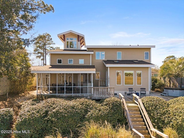 rear view of property with a sunroom, fence, and stairway