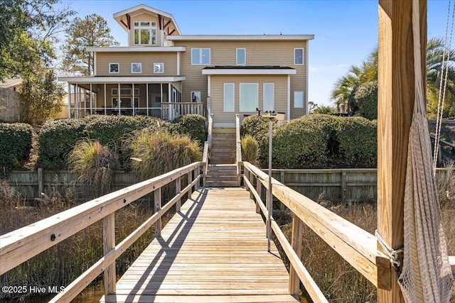 rear view of property with stairway, fence, and a sunroom