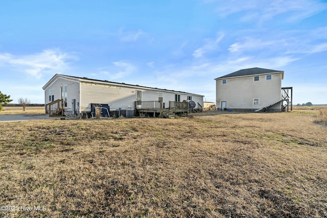 rear view of house featuring central AC, a deck, and a lawn