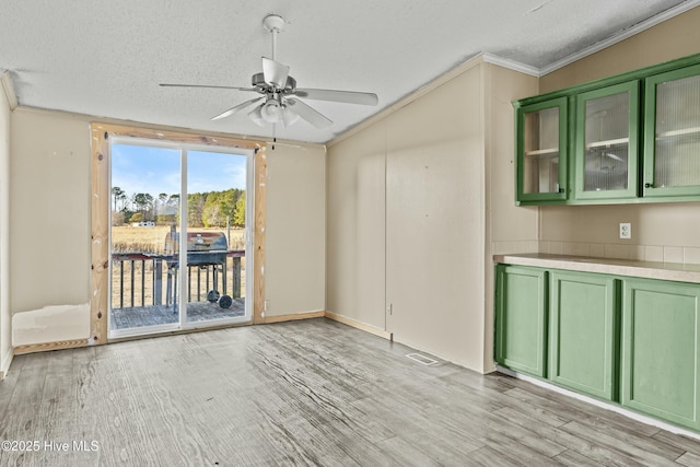 interior space with crown molding, light hardwood / wood-style floors, ceiling fan, and a textured ceiling