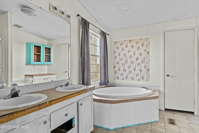 bathroom with a bathing tub, tile patterned floors, vanity, and a textured ceiling