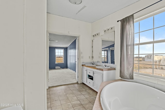 bathroom featuring tile patterned floors, vanity, and a washtub