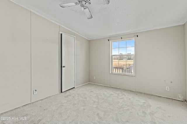 carpeted spare room featuring ceiling fan and a textured ceiling