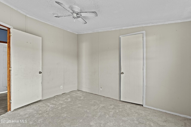 empty room with ceiling fan, light carpet, and a textured ceiling