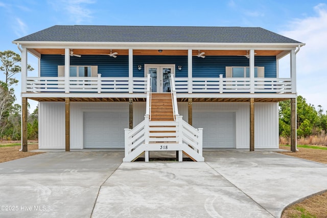 view of front facade with an attached garage, a shingled roof, stairs, and a ceiling fan