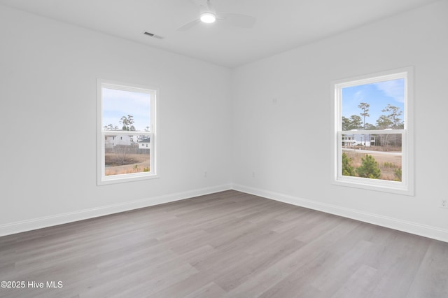 empty room featuring light wood-type flooring, visible vents, ceiling fan, and baseboards