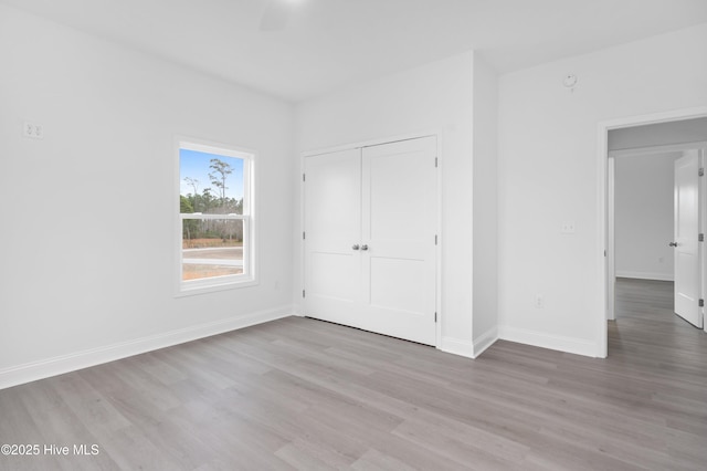 unfurnished bedroom with a closet, light wood-type flooring, and baseboards