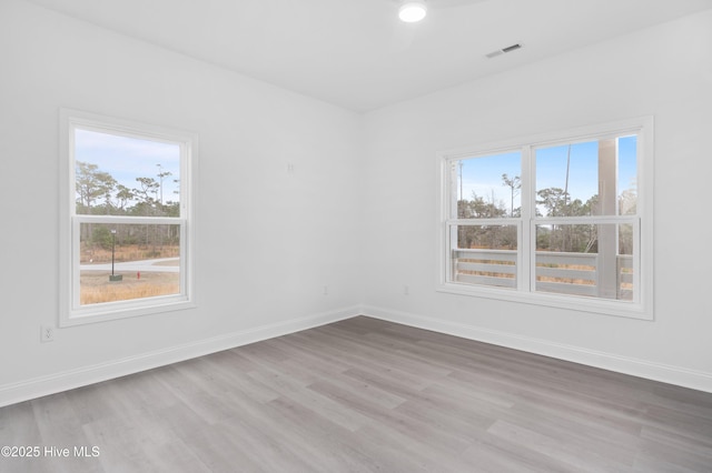 empty room with light wood-type flooring, visible vents, and baseboards