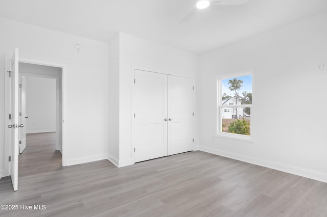 unfurnished bedroom with ceiling fan, a closet, light wood-type flooring, and baseboards