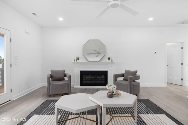 living area featuring ceiling fan, recessed lighting, a fireplace, and wood finished floors