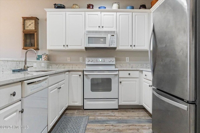 kitchen with white appliances, light stone countertops, sink, and white cabinets