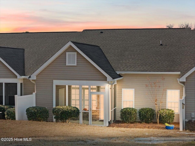 exterior space with a sunroom and a shingled roof