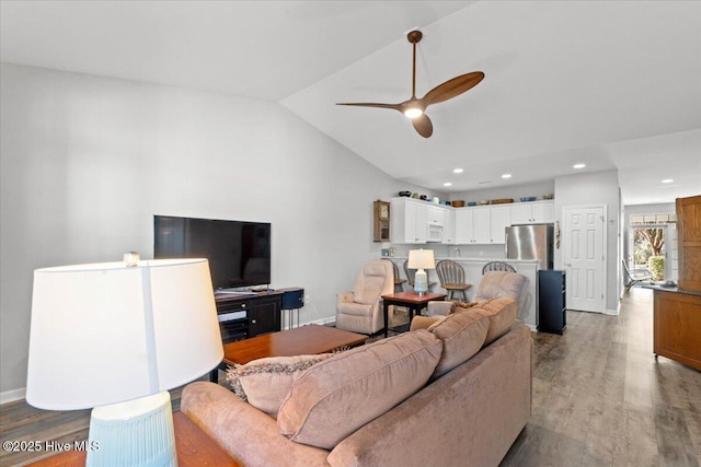 living room featuring ceiling fan, lofted ceiling, and light hardwood / wood-style floors