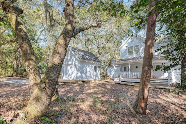 back of property with a garage, an outbuilding, and a porch