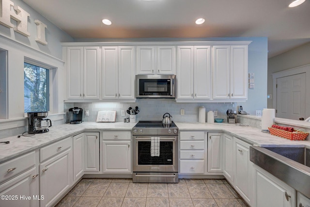 kitchen featuring decorative backsplash, light tile patterned flooring, white cabinets, and appliances with stainless steel finishes