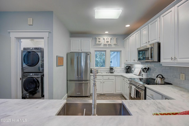 kitchen with white cabinetry, premium appliances, decorative backsplash, and stacked washer and dryer