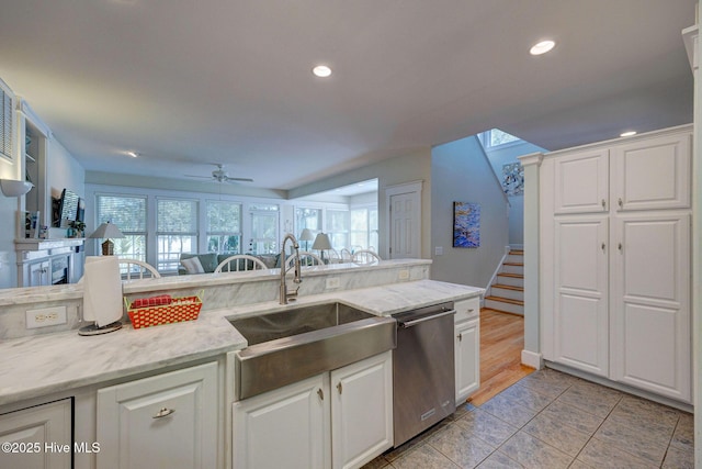 kitchen featuring stainless steel dishwasher, sink, and white cabinets