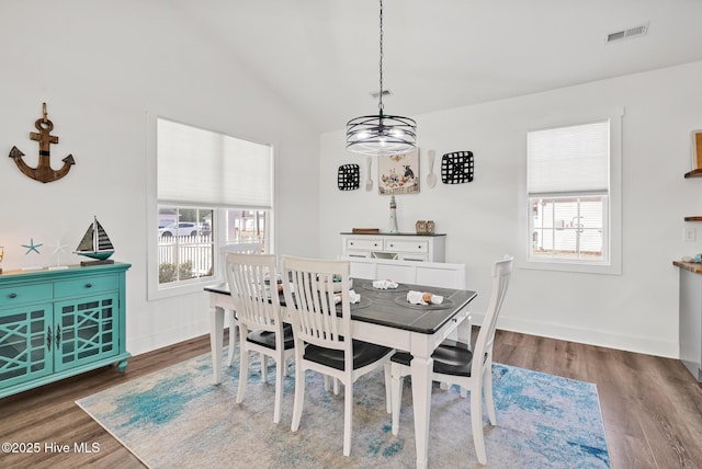 dining space featuring dark hardwood / wood-style flooring and vaulted ceiling