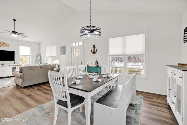 dining space featuring high vaulted ceiling, wood-type flooring, and ceiling fan with notable chandelier