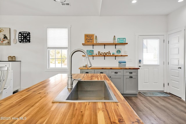 kitchen with wood counters, sink, gray cabinetry, and light wood-type flooring