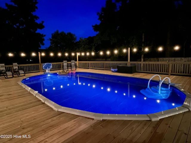 pool at twilight featuring a wooden deck