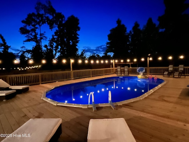 pool at night with a wooden deck