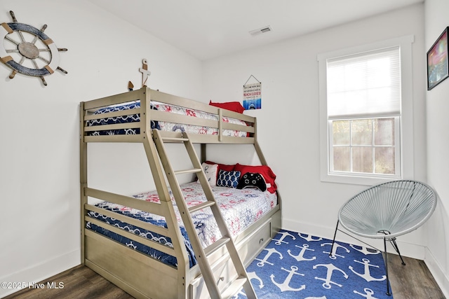 bedroom with multiple windows and dark wood-type flooring