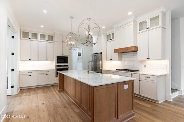 kitchen featuring white cabinetry, light stone countertops, an island with sink, and appliances with stainless steel finishes