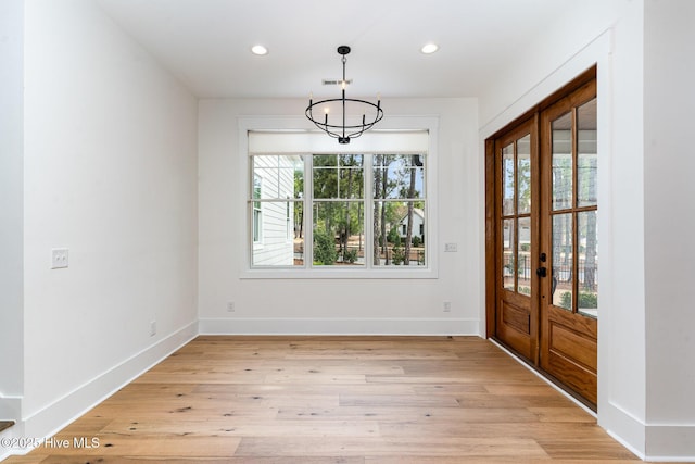 unfurnished dining area with a chandelier and light hardwood / wood-style floors