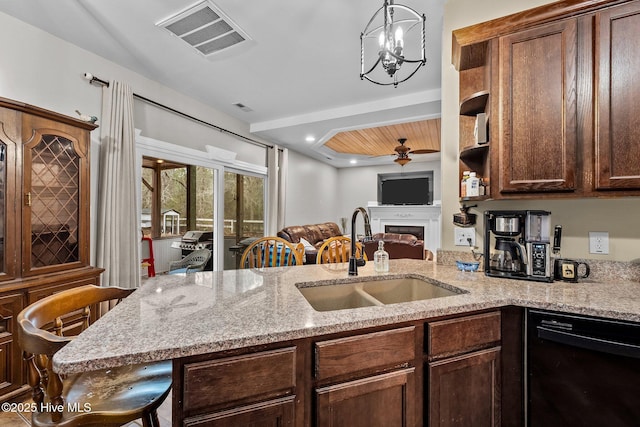 kitchen featuring light stone counters, sink, black dishwasher, and ceiling fan