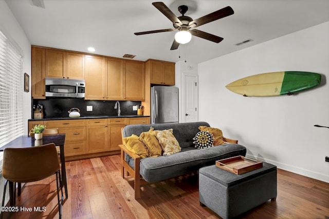 living room featuring hardwood / wood-style flooring, sink, and ceiling fan