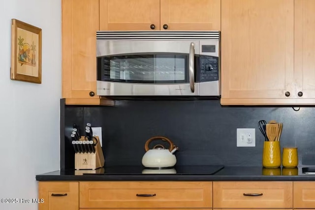 kitchen featuring black stovetop, light brown cabinetry, and decorative backsplash