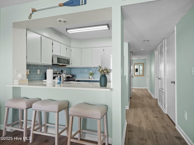 kitchen with sink, a breakfast bar area, white cabinets, and backsplash