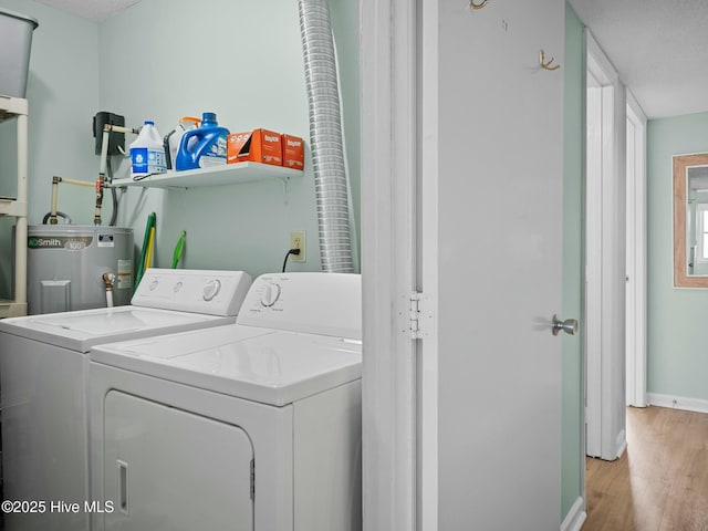 laundry room with electric water heater, washer and clothes dryer, and light hardwood / wood-style flooring